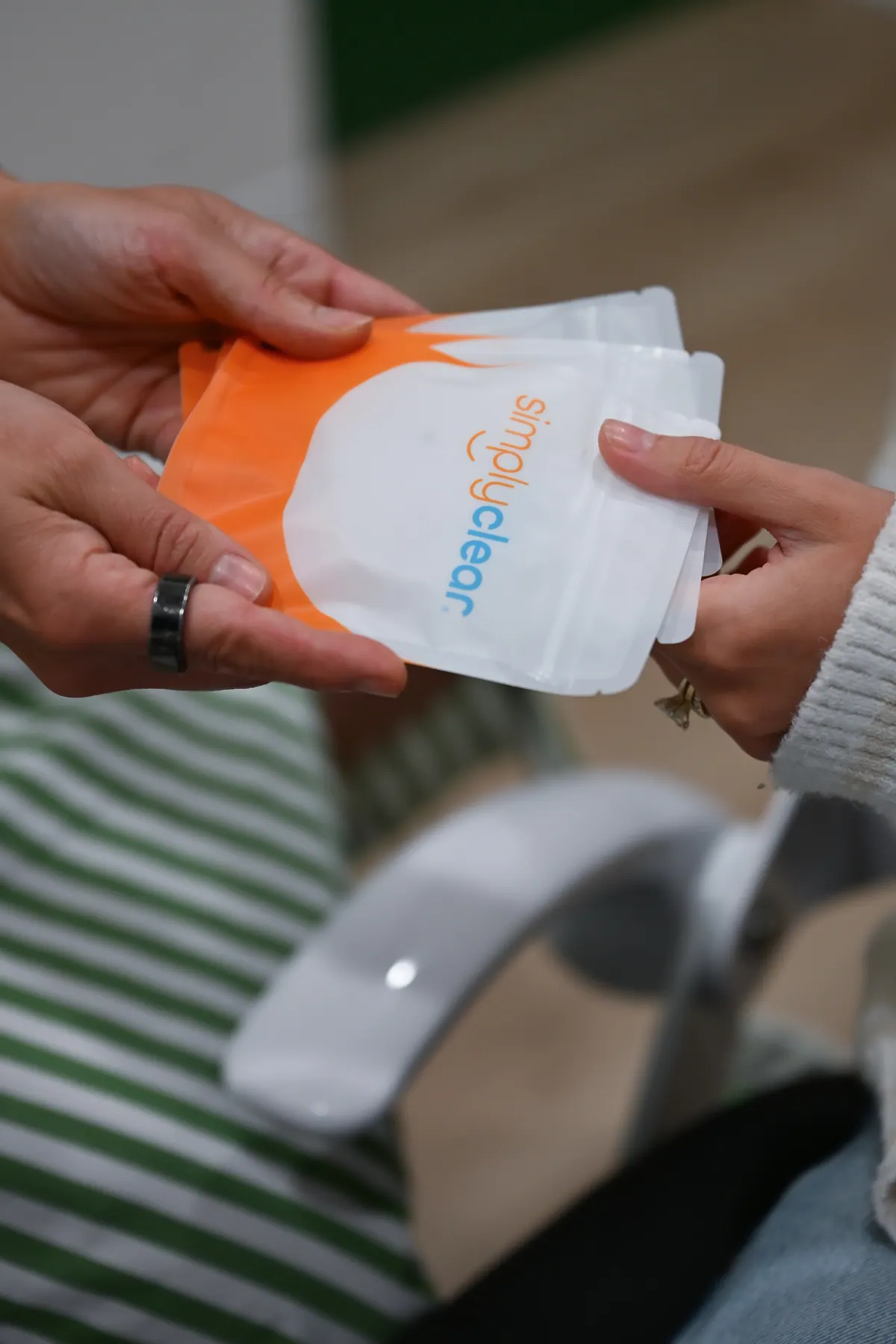 Hands holding a SimplyClear® pouch and aligner